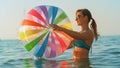 CLOSE UP: Smiling woman having fun in the ocean spins a large ball in her hands. Royalty Free Stock Photo