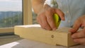 CLOSE UP: Unrecognizable builder uses a tape measure to inspect a block of wood.