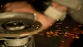 CLOSE UP: Unrecognizable worker steel grinding a workpiece in his dark workshop.