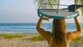 CLOSE UP Woman carries a surfboard on her head while walking to beach at sunrise Royalty Free Stock Photo