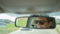 CLOSE UP, DOF: Young Caucasian male smiles while driving his car down the road.