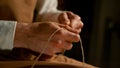 CLOSE UP, DOF: Young shoemaking apprentice preparing yarn in the workshop.