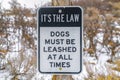 Close up of a Dog Leash sign on a wooden post against a snowy landscape Royalty Free Stock Photo