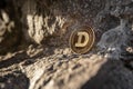 Single Dogecoin coin on a rock outdoor with copy space
