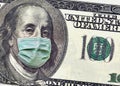 A close up of a 100 dollar bill shows Benjamin Franklin wearing a surgical mask