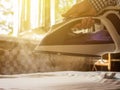 Close up domestic iron with steam go out houswork over the table ironing clothes against sunrays Royalty Free Stock Photo