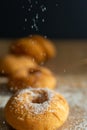 Close-up of donuts with black out of focus background and sugar falling