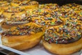 Donuts with colorful sprinkles arranged on tray at bakery shop