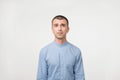 Close up of a doubtful young man in blue shirt. He is not sure what to do. Royalty Free Stock Photo