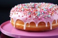 Close up doughnut with pink icing and sprinkles isolated on solid background