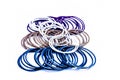 Close up of dozen of white and blue colored bangles along with a dozen  of purple and orange colored bangles isolated on white. Royalty Free Stock Photo