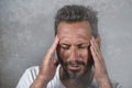 Close up dramatic portrait of young attractive anxious and depressed man in pain with hands on his head suffering headache and