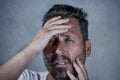 Close up dramatic  portrait of young attractive anxious and depressed man in pain with hands on his head suffering headache and Royalty Free Stock Photo