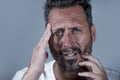 Close up dramatic  portrait of young attractive anxious and depressed man in pain with hands on his head suffering headache and Royalty Free Stock Photo