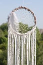 Close up dream catcher hanging over the azure lake, bohemian craft outdoors