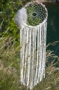 Close up dream catcher hanging over the azure lake, bohemian craft outdoors