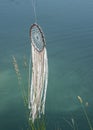 Close up dream catcher hanging over the azure lake, bohemian craft outdoors