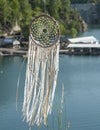 Close up dream catcher hanging over the azure lake, bohemian craft outdoors