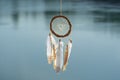 Close up dream catcher hanging over the azure lake, bohemian craft outdoors