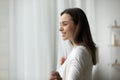 Close up dreamy smiling young woman opening curtains in morning Royalty Free Stock Photo