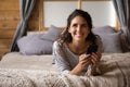 Close up dreamy young woman holding phone, relaxing on bed Royalty Free Stock Photo