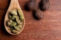dried cardamom pods in spoon with nutmeg on wooden background, asia spice for cooking