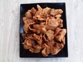 Close-up dried fried banana chips indonesian cuisine snack on the black plate with silver background