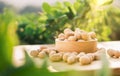 Dried peanuts in wooden bowl on table with green peanut plantation background