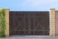 A close up of a driveaway dark wood closed gates at the clear blue sky background. Entry gate of a country house. Driveaway gates