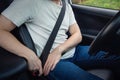 Close up driver fastening the seat belt. Person seated behind the steering wheel testing his new car safety. Secure transportation Royalty Free Stock Photo