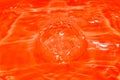 Close up of drop splash in water with orange background. Shiny rippled Surface texture and design. Royalty Free Stock Photo