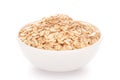 Close-up of dry organic whole rolled oats Avena sativa roasted in a white ceramic bowl over white background Royalty Free Stock Photo