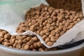 Close-up of dry pelleted pet food. Brown round pellets inside an open white bag. Pet food Royalty Free Stock Photo