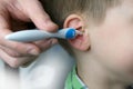 Close-up ear child, kid, adult hand gently cleans the inner ear, Spiral Silicone Earwax Remover blue, modern hygiene concept, Royalty Free Stock Photo