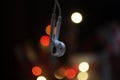 Close up of earphone hanging with colorful bokeh light on dark background. Copy space Royalty Free Stock Photo