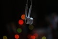 Close up of earphone hanging with colorful bokeh light on dark background. Copy space Royalty Free Stock Photo