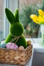 Close Up Easter Bunny Rabbit In Straw Basket With Colored Eggs On The Windowsill With Fresh Spring Tulips And Daffodils Flowers