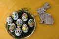 Close up on easter eggs and a wooden easter bunny on a yellow tablecloth with copy space