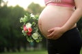 Close-up of Eastern Asian Chiense pregnant woman`s belly, flowers on belly, grass meadows as background in nature outdoor healthy Royalty Free Stock Photo