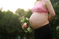 Close-up of Eastern Asian Chiense pregnant woman`s belly, flowers on belly, grass meadows as background in nature outdoor healthy Royalty Free Stock Photo