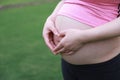 Close-up of Eastern Asian Chiense pregnant woman`s belly, hands with love-shape gesture on belly. mother love baby family concept