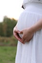 Close-up of Eastern Asian Chiense pregnant woman`s belly, hands with love-shape gesture on belly. mother love baby family concept