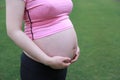 Close-up of Eastern Asian Chiense pregnant woman`s belly, hands touch on belly outdoor nature. mother love baby family concept