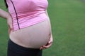 Close-up of Eastern Asian Chiense pregnant woman`s belly, hands touch on belly outdoor nature. mother love baby family concept