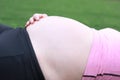 Close-up of Eastern Asian Chiense pregnant woman`s belly, lying on grass meadow field enjoy free casual time in nature outdoor Royalty Free Stock Photo