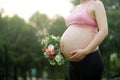 Close-up of Eastern Asian Chiense pregnant woman`s belly, flowers on belly, grass meadows as background in nature outdoor healthy Royalty Free Stock Photo