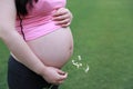 Close-up of Eastern Asian Chiense pregnant woman`s belly, flowers on belly, grass meadows as background in nature outdoor healthy Royalty Free Stock Photo