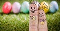 Close-up of eastern bunnies cartoon drawing on fingers against eggs on grass