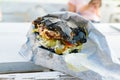 Close-up eaten black fast food burger. Background girls teenagers, outdoor summer cafe Royalty Free Stock Photo