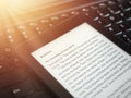 Close up of ebook reader with The Holy Bible on a laptop keyboard, with sun rays light concept Royalty Free Stock Photo